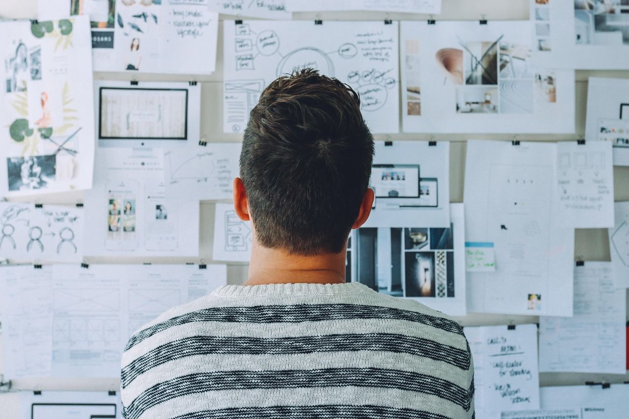A man studying a wall of sketches and wireframes.